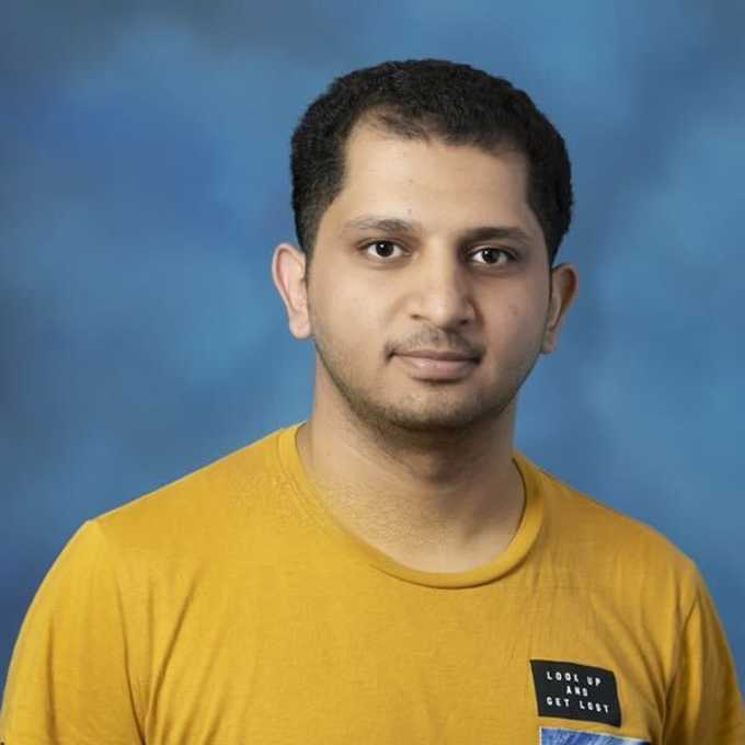 A young man wearing a yellow teeshirt appears on a blue background